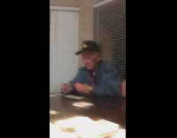 old man blue jacket plays card game