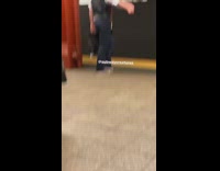 Man red black vest sings loud with earphones on in subway train