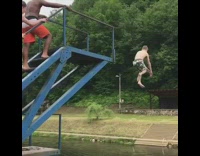kid in orange shorts belly flops into lake