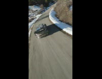 Drone footage following a racer in a car driving through a windy road 