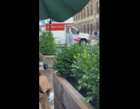 Hospital gown guy crosses street smokes cigarette 