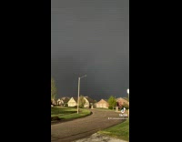 Lightning in distance of houses covered in sunlight