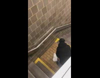 Guy black sweater jeans squats escalator stairs