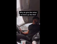 Guy looks back while backing up car