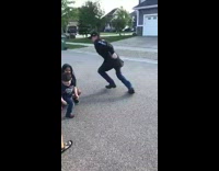 Guy plays basketball with little kids, makes one fall and shoots ball into hoop on the street