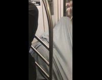 Guy covers himself in gray tarp sheet and sleeps on subway train