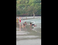 Woman in black bikini bends on the beach