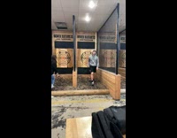 Guy reverse throws axe onto bullseye at range
