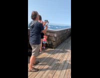 Man white shirt spread arms while a man films behind him