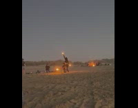 Two women fire dance beach sand sundown