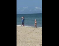 Woman bikini dances behind man selfie tiktok beach
