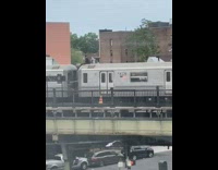Guy sitting down on top of subway train departing from station 
