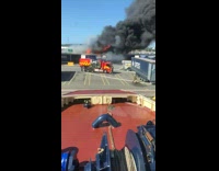 Red boat goes towards fire smoke port