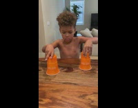 Kid performs disappearing orange trick under cups