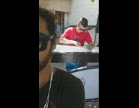 Man red shirt waxes surfboard on outdoor patio guy records selfie video