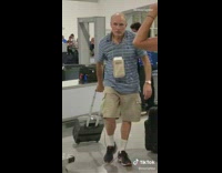 Dad pulls grey luggage handle up airport 