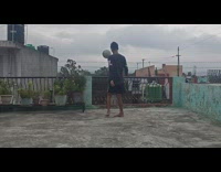 Barefoot guy bounces white ball over balcony 