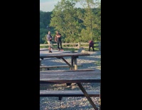 Woman ripped jeans sit on wooden fence sunset