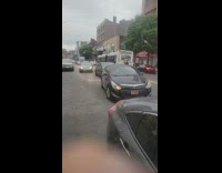 Guy holds onto the back of bus 