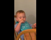 Baby with a bib sits on a chair play  and make sounds