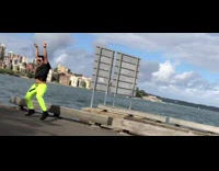 Man in neon pants hip thrusts next to ocean