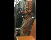 Woman in orange tiger suit costume writes in journal on subway train