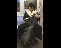 man with elvis costume carrying large instrument case