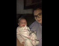Girl holding sad looking baby throws up