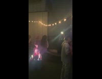 Woman violet outfit hugs pink statue at a party