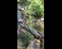 Girl lays back holds tree log waterfall