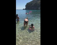 Young boy behind girl bikini beach floatie