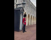 Two women poses beside the queen's guard
