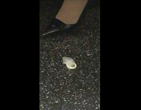 Open used condom on subway train floor next to womens foot 
