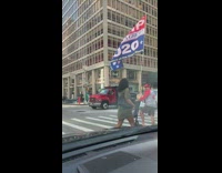 Man rides electric scooter with big Trump 2020 flag on the street