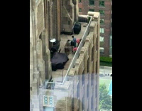 Guy on rooftop porch of a building djing on a table to himself 

