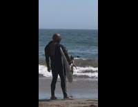 Black unzipped wetsuit guy white surfboard beach 