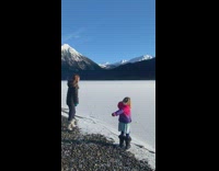 Two girls throw rock on frozen lake