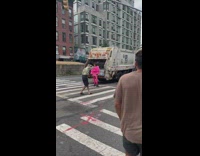 Woman in pink poses in front of garbage truck 