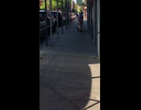 Lady pushes cart down sidewalk plastic poncho 