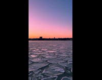 Pieces of ice float on river sunset