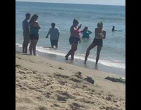 Girl puts hand behind neck and takes pictures at beach