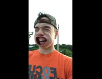 Orange Shirt Backwards Hat Leaf Blower in Mouth