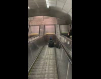 Blue hat guy sits on down escalator 