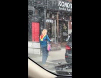 Woman blue jacket feeds pigeons on street