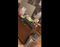 Guy in kitchen keeps pouring coke in cup and spills on floor