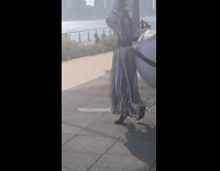 Woman white fluffy har striped dress white face paint dances to violin music with inflatable globe on her back 