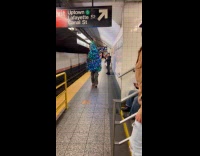 Collab WINY - Man in Christmas tree costume walking beside subway rail