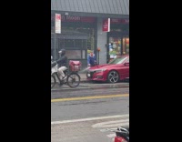 Guy wash his red car along the street at day 