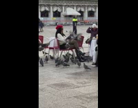 Woman in white top and red beret poses with pigeons on her