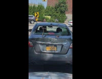 Gray car drives with broken back window 